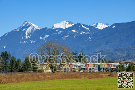 New residential townhouses on blue sky and mountain background. Winter season in Fraser valley, British Columbia