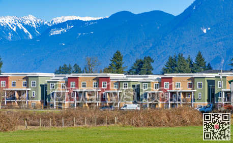 New residential townhouses on blue sky and mountain background. Winter season in Fraser valley, British Columbia