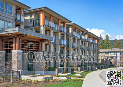 New residential apartment building with walkway and bike route in front on sunny day in British Columbia, Canada