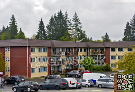 Low-rise residential building with cars parked in front on overcast rainy day