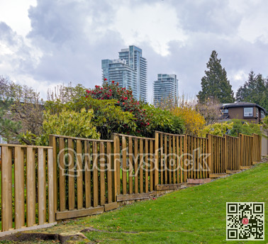 Wooden fenc in residential area with high-rise buildings on cloudy sky background